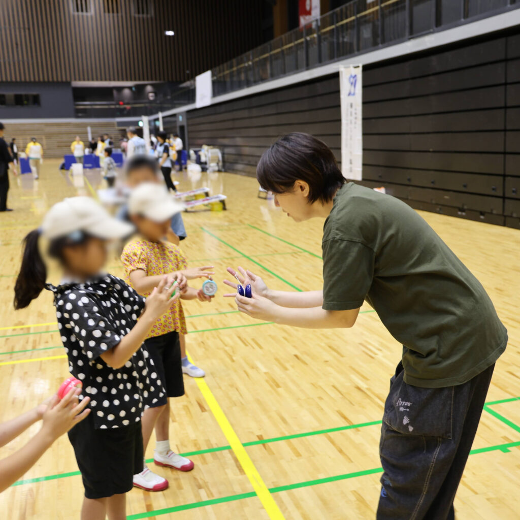 ヨーヨーの持ち方や投げ方を熱心に聞く子どもたちの様子